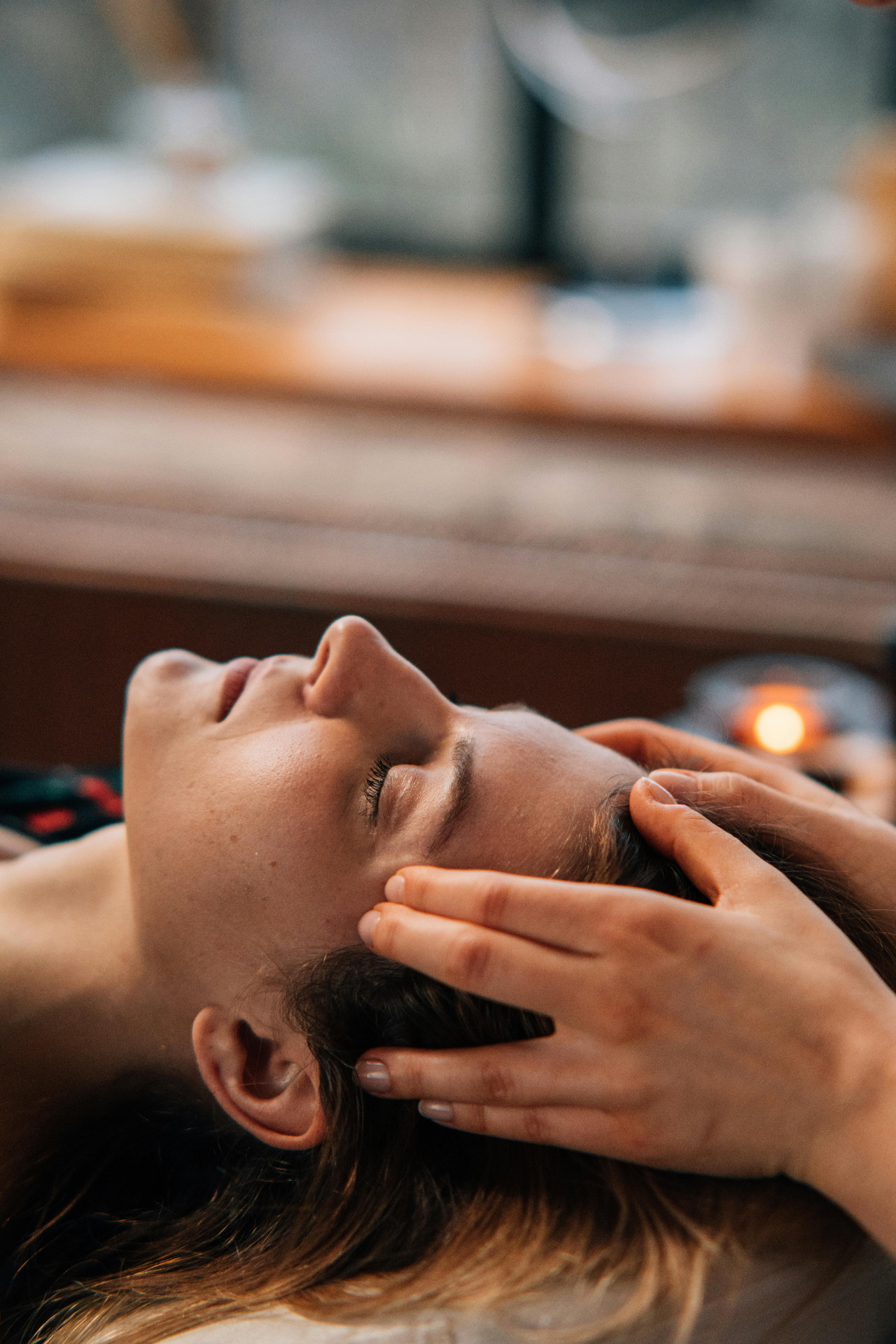 In-person Reiki session in San Diego with light touch near the head, in soft candlelight